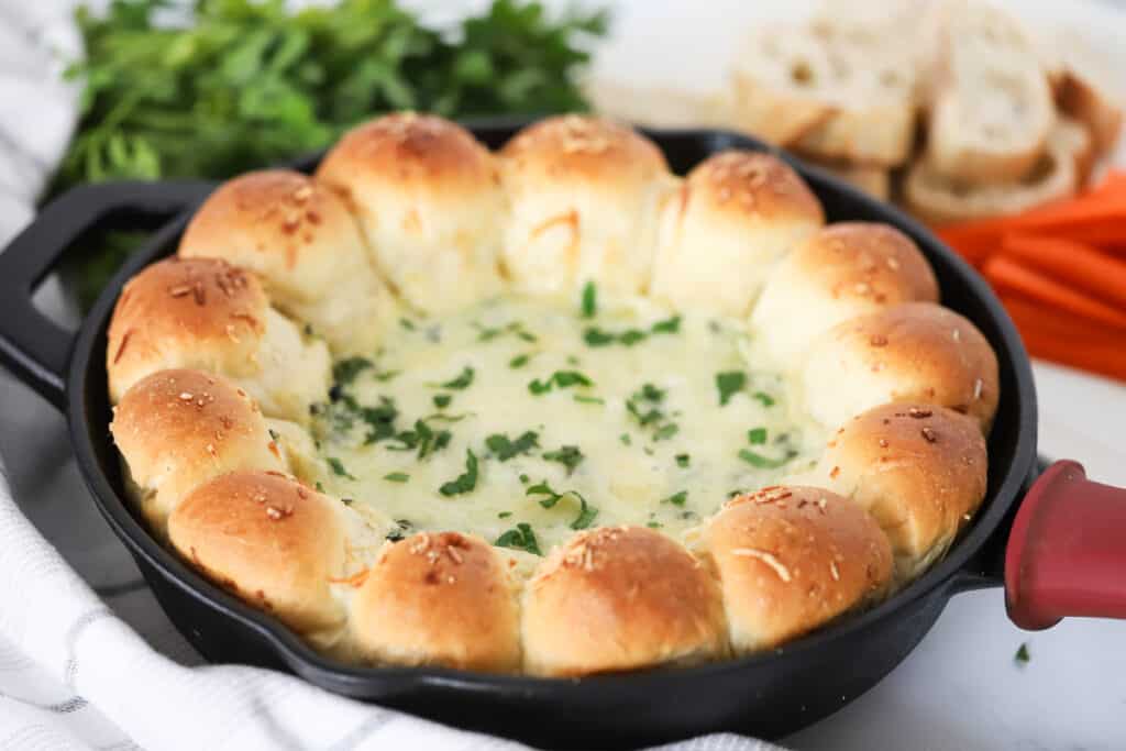 A cast iron skillet with a Spinach Dip Bread Ring baked into it.