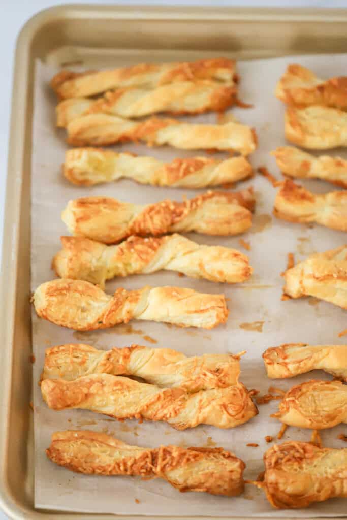 A baking sheet full of Cheese Twists made with puff pastry. Puff Pastry cheese straws are an easy appetizer recipe. Cheese straws recipe puff pastry.