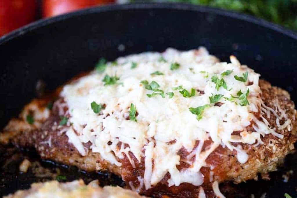 chicken parmesan with melted mozzarella cheese in a pan. 