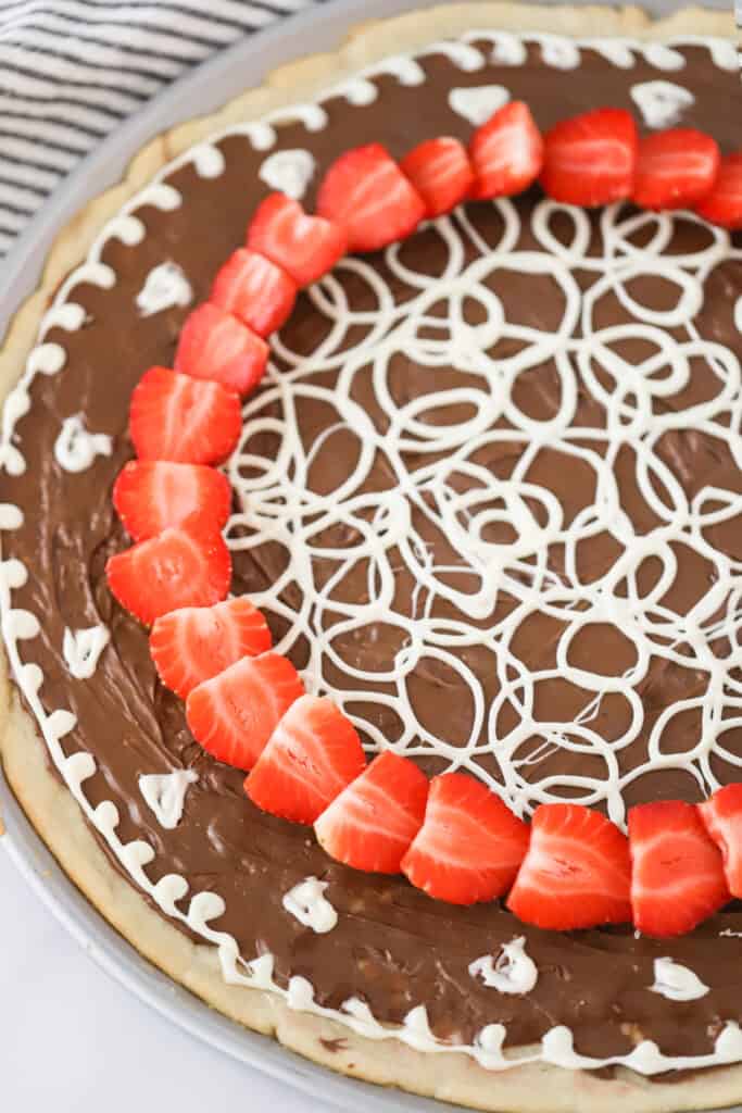 Dessert pizza topped with Nutella, strawberries, and white chocolate. recipe for nutella pizza. 