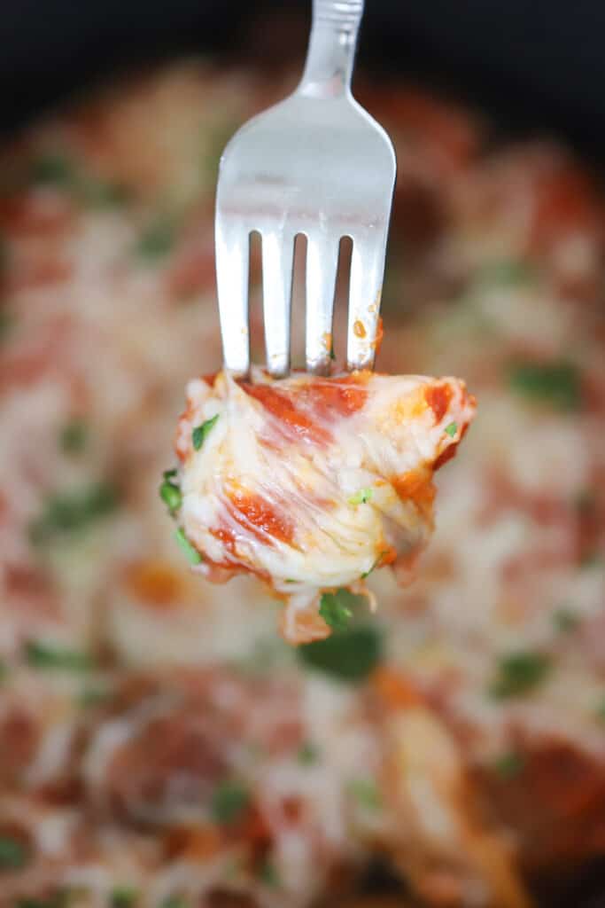 A fork holding a cheesy Italian meatball; frozen meatballs crockpot.