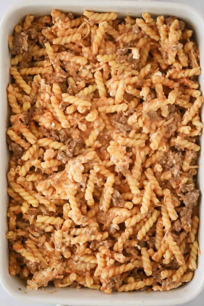 Pasta and ground beef covered with a cheesy sauce inside a baking dish.