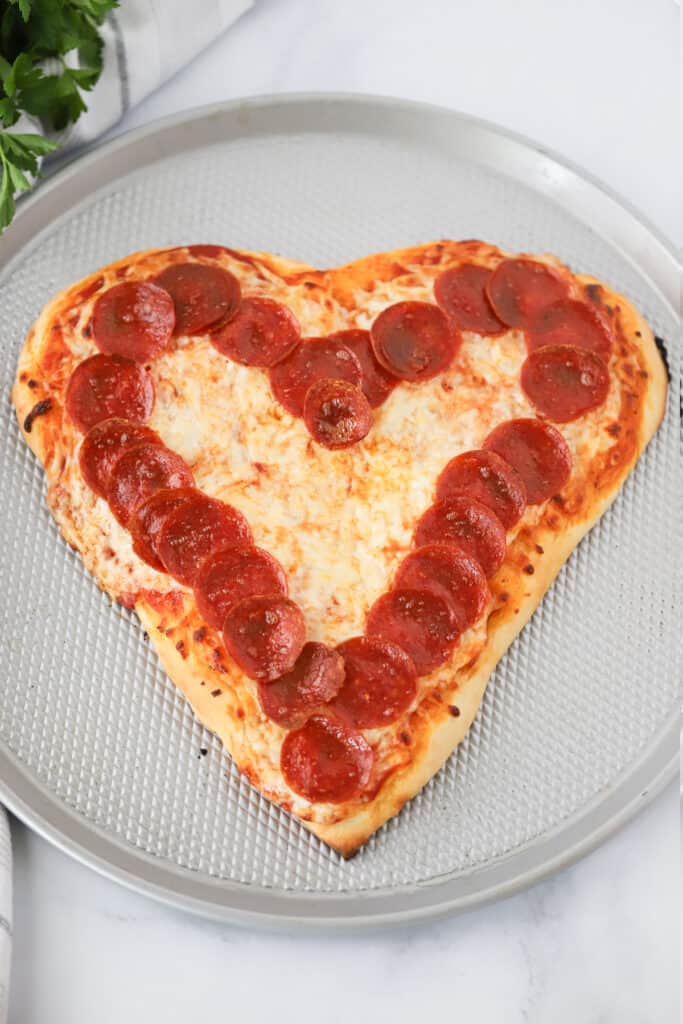 A Heart Shaped Pizza on a pizza pan with a ring of pepperonis around the edge. How to make a heart shaped pizza. Pizza heart. 
