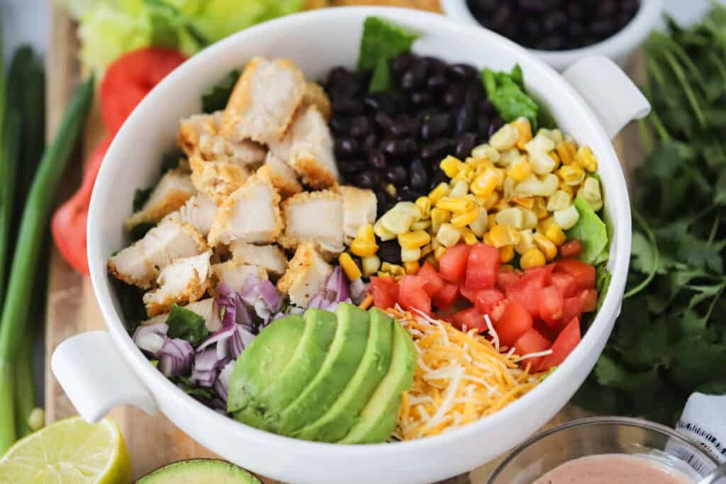 Southwest Crispy Chicken Salad in a bowl with fresh limes and cilantro surrounding it.