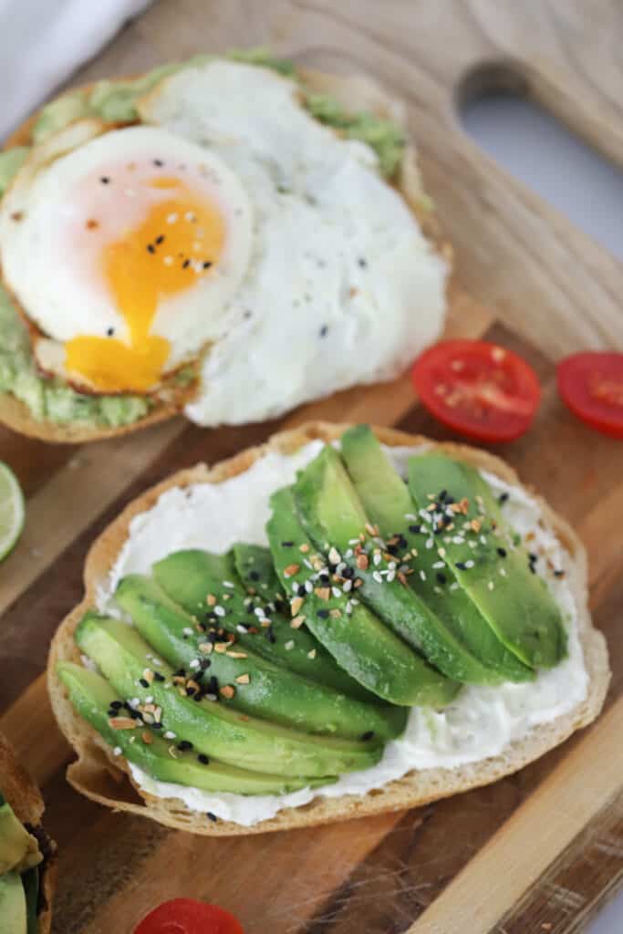 A cutting board with toast topped with sliced avocados and seasoning; Avocado toast recipe easy, avocado toast seasoning, simple avocado toast with egg.