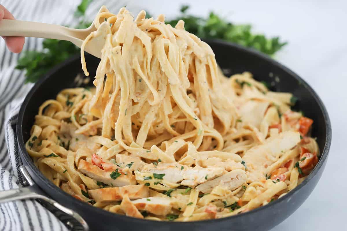 Spicy Cajun Chicken Pasta 3 A saute pan filled with spicy Cajun pasta Alfredo, featuring tender chicken pieces and a rich, creamy sauce.