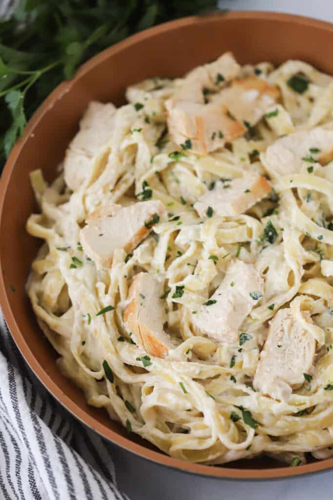 A bowl full of Chicken Alfredo with fettuccine pasta.