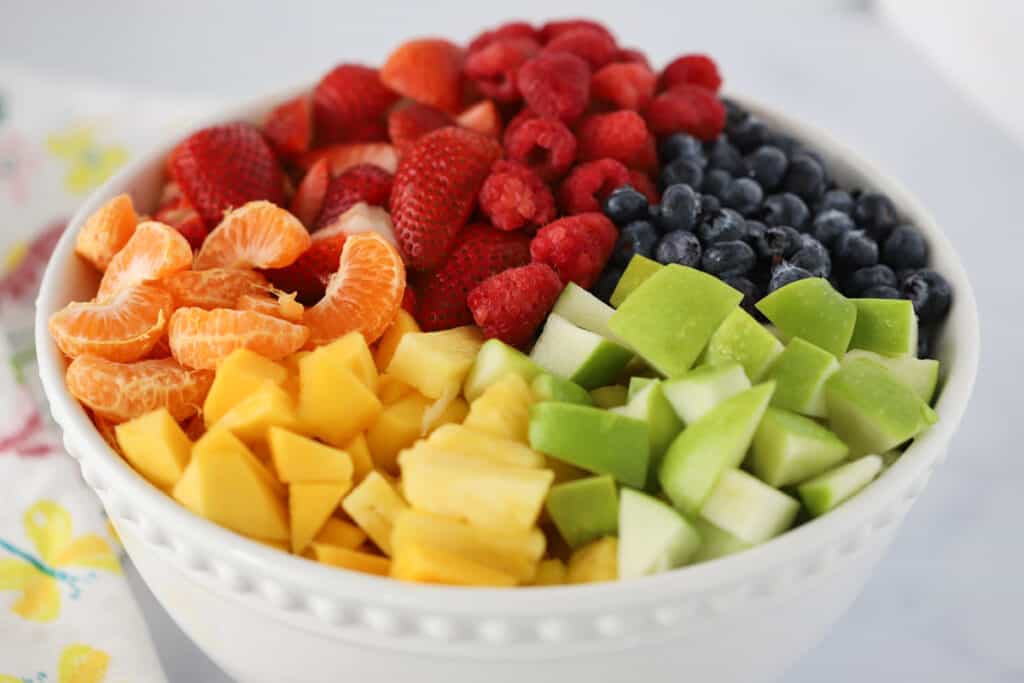 This colorful rainbow Fruit Salad recipe served in a white ceramic bowl.
