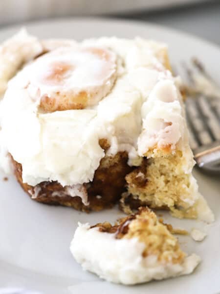 einkorn cinnamon roll on a white plate with frosting