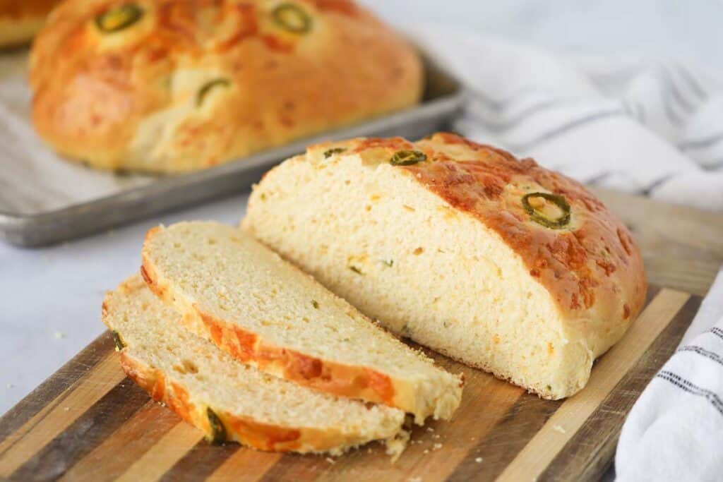 Sliced cheddar jalapeno bread on a cutting board, how to make homemade bread, cheesy bread recipe.
