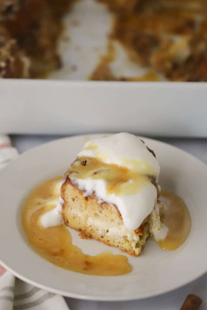 A white serving plate with a slice of pumpkin stuffed French toast topped with whipped cream.
