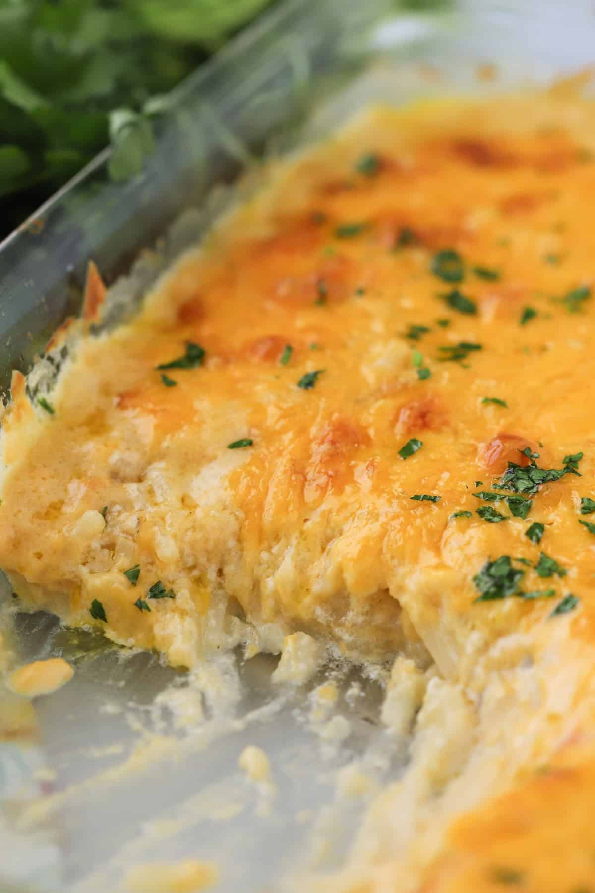 cheesy potato casserole in a glass baking dish, amazing potato side dish recipe for family dinner.