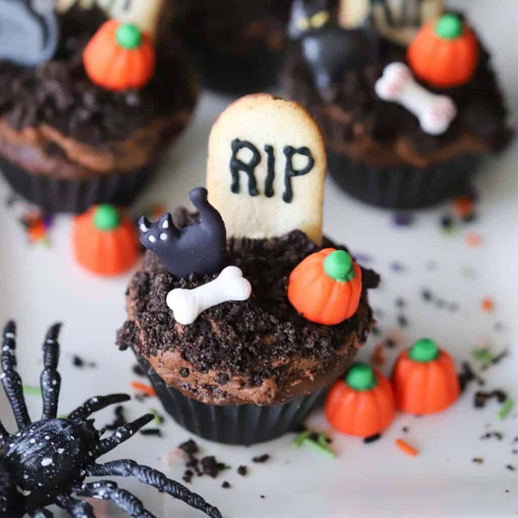 graveyard cupcakes decorated with little candy pumpkins and bones.