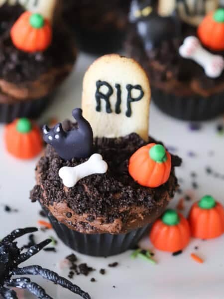 graveyard cupcakes decorated with little candy pumpkins and bones.