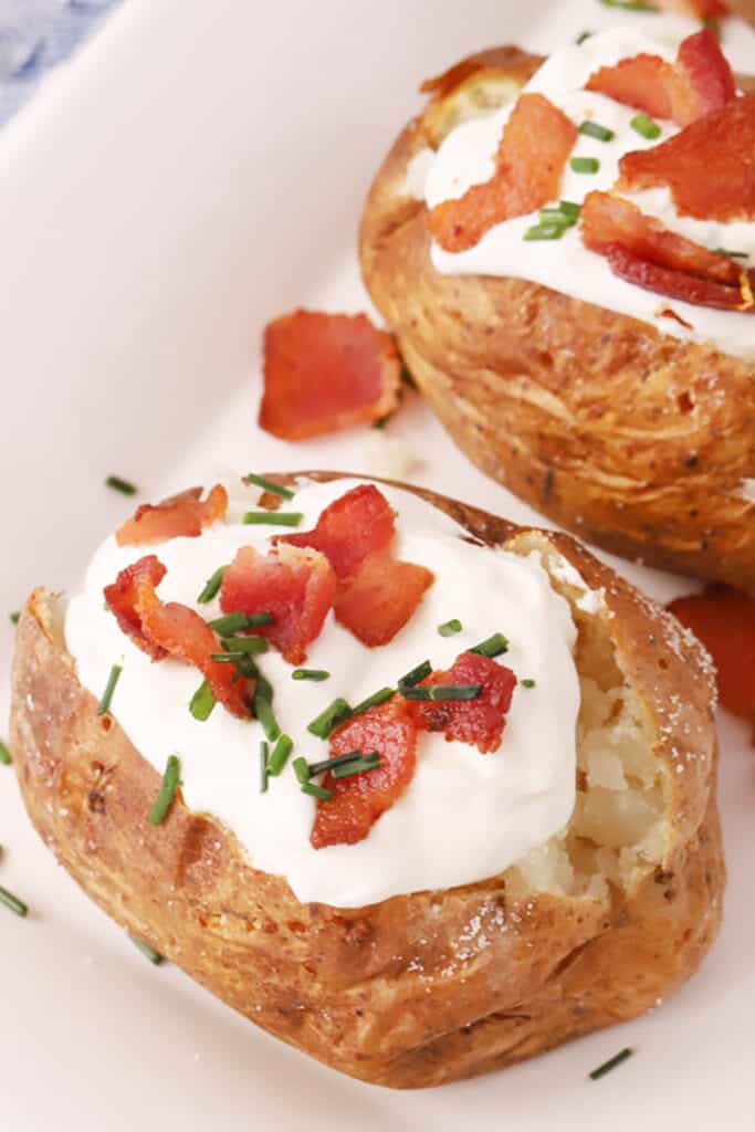 air fryer baked potatoes with toppings, sour cream, bacon bits, and chives. how long to bake a potato in an air fryer, baked potato in a convection oven.