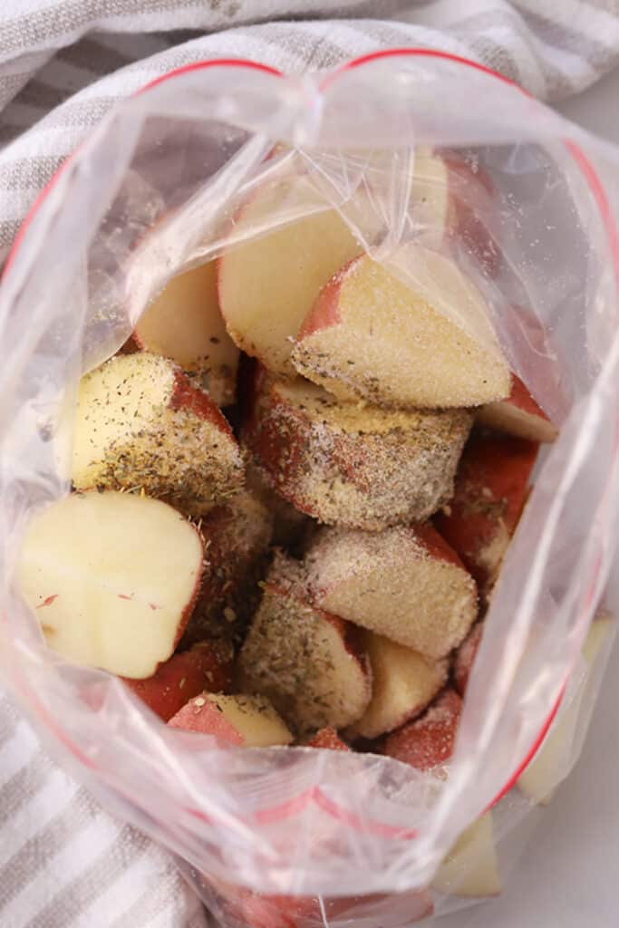 how to make roasted red potatoes air fryer recipe,  A ziplock bag filled with quartered potatoes and seasoning.