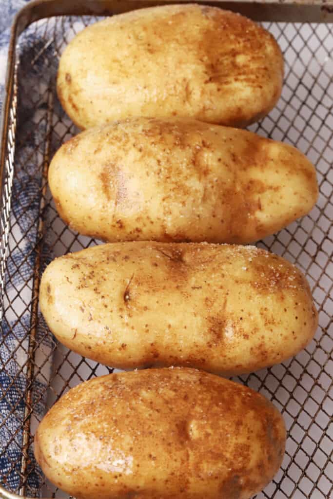 uncooked air fryer baked potatoes recipe in air fryer basket, air fryer baked potato recipe.