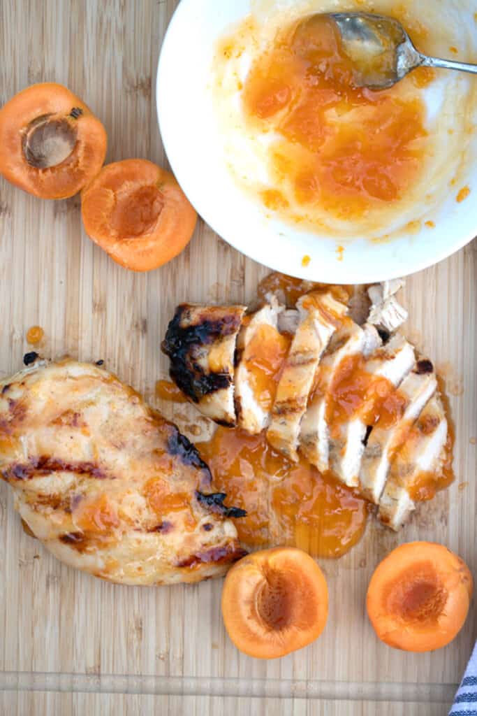 apricot chicken glaze with chicken breast on a wood cutting board with fresh apricots, chicken with apricot jam, apricot chicken breast, traditional apricot chicken recipe.