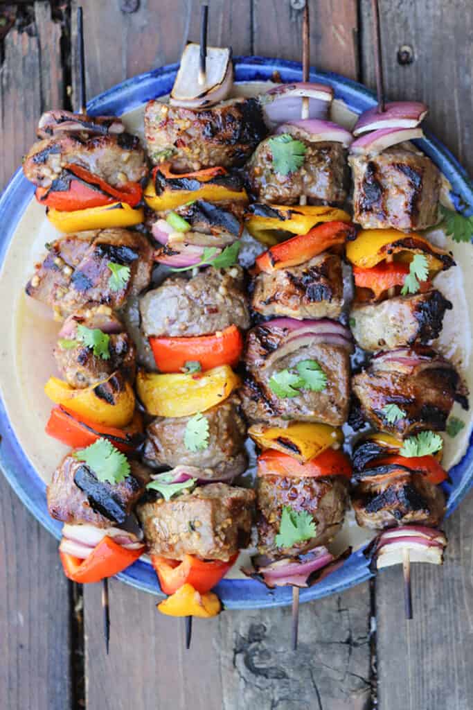 Asian Beef Steak kabobs on a blue platter, topped with fresh cilantro, beef kabob recipes, marinated shish kabobs. 
