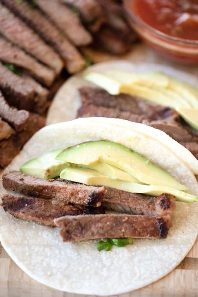 Flour tortillas with carne asada meat and sliced avocados.