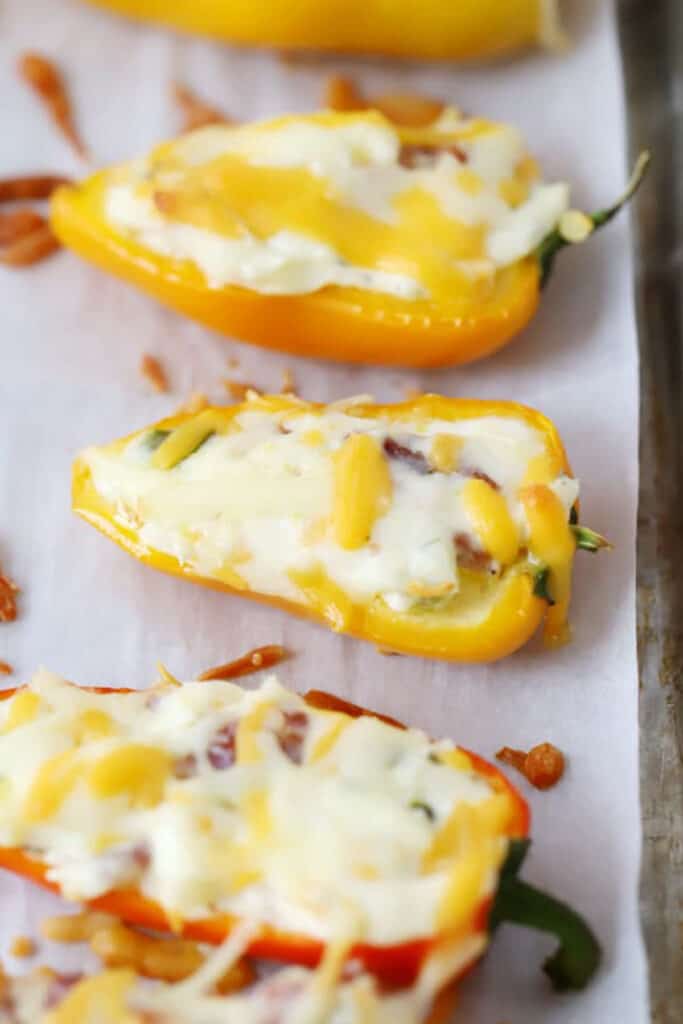 Stuffed bell peppers and cream cheese baked and resting on a baking sheet.