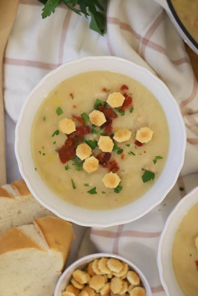 Creamy manhattan clam chowder in a bowl topped with oyster crackers, bacon, and parsley. This is the best clam chowder recipe that tastes like it came from a restaurant.