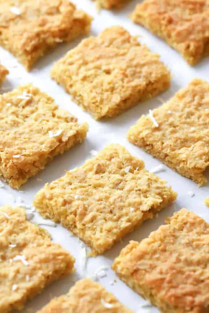 Coconut Cookie Bars cut into squares and lined up a baking sheet. These oatmeal coconut bars are an easy and sweet treat.