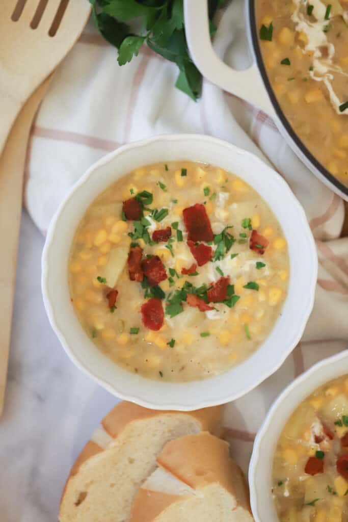 A bowl full of potato corn chowder topped with bacon bits and chives. It's an easy corn chowder recipe that's super creamy and can be made with fresh or frozen corn.