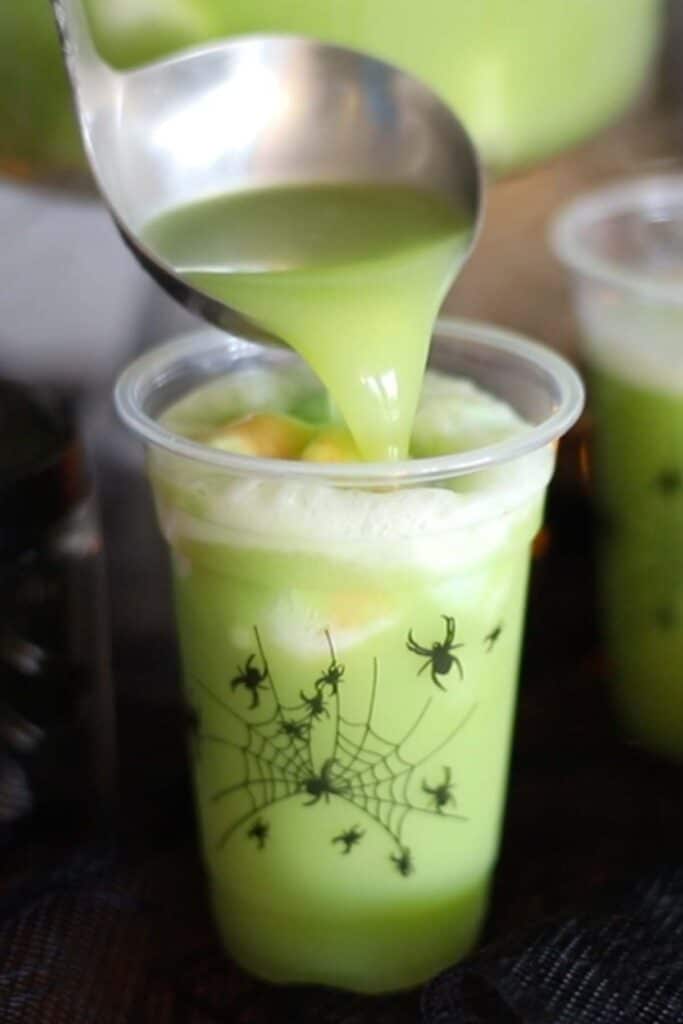 Spooky green halloween punch in a festive cup. It's great to serve along with other halloween treats.
