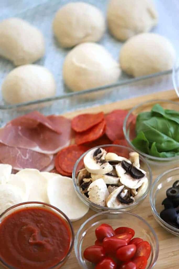 Ramekins of ingredients with a baking dish behind with rolled pieces of dough.