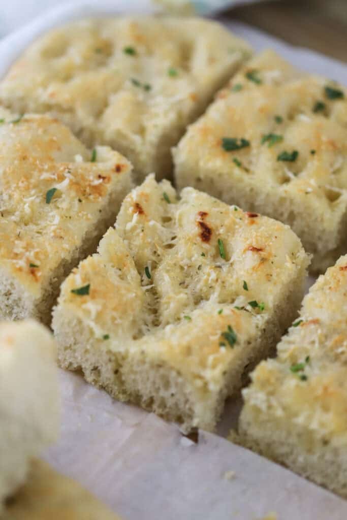 herb focaccia bread cut up into squares to be served.