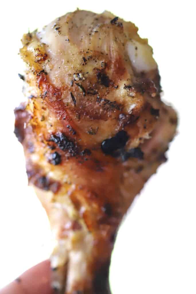 A hand holding a crispy chicken drumstick.