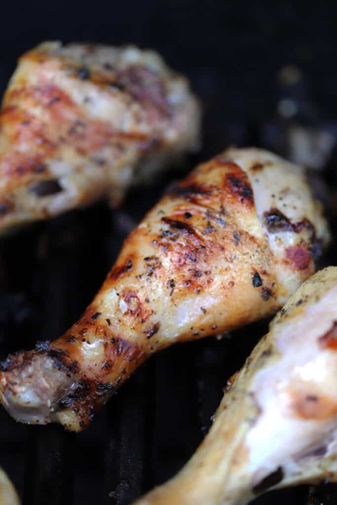 Chicken legs on a grill with golden brown char marks.