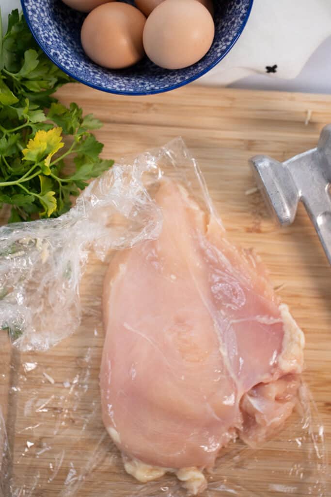 Pounded chicken on a wooden cutting board.