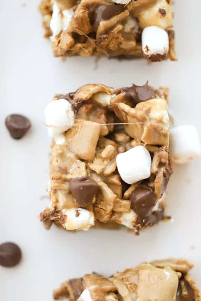 S'mores Bars on a tabletop sprinkled with mini marshmallows and chocolate chips. S'mores bar recipe golden grahams.