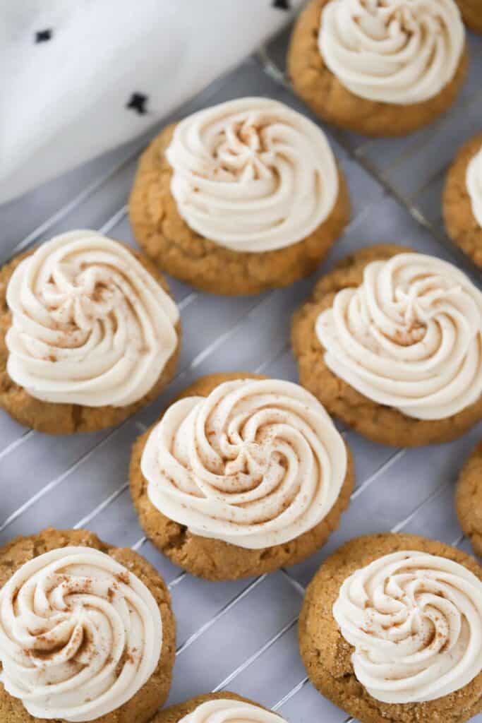 Cream cheese frosting for pumpkin cookies piped over the top. These soft pumpkin cookies with cream cheese are resting on a wire rack.