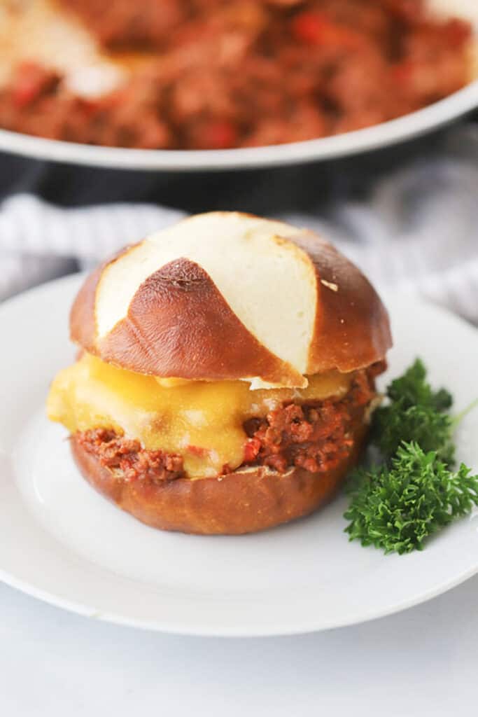 Old fashioned sloppy joe on a bun with melted cheese and a sprig of parsley. 
