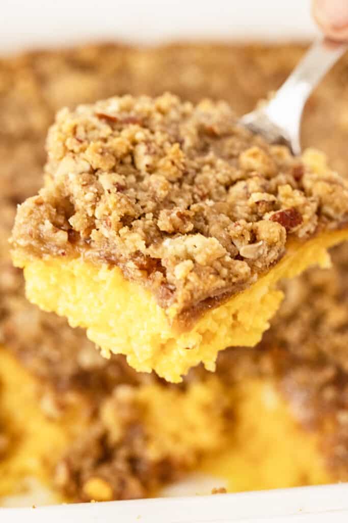 Sweet potato casserole with pecan topping in a baking dish with a serving removed. 