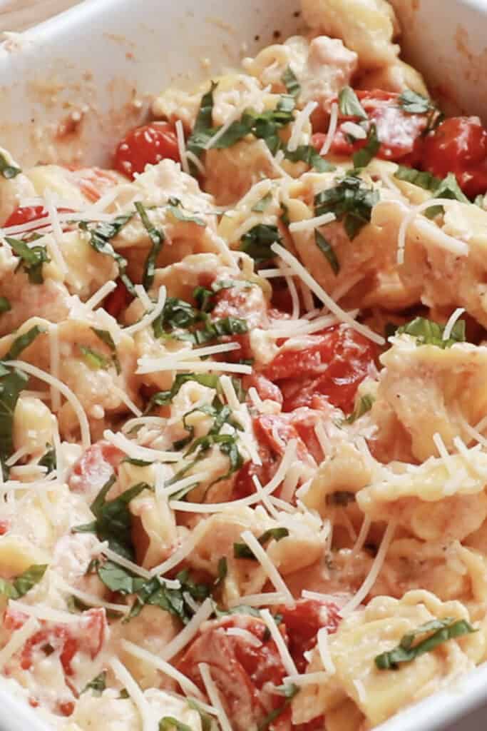 tikok feta tomato pasta recipe mixed in a white baking dish, feta cheese pasta recipes.