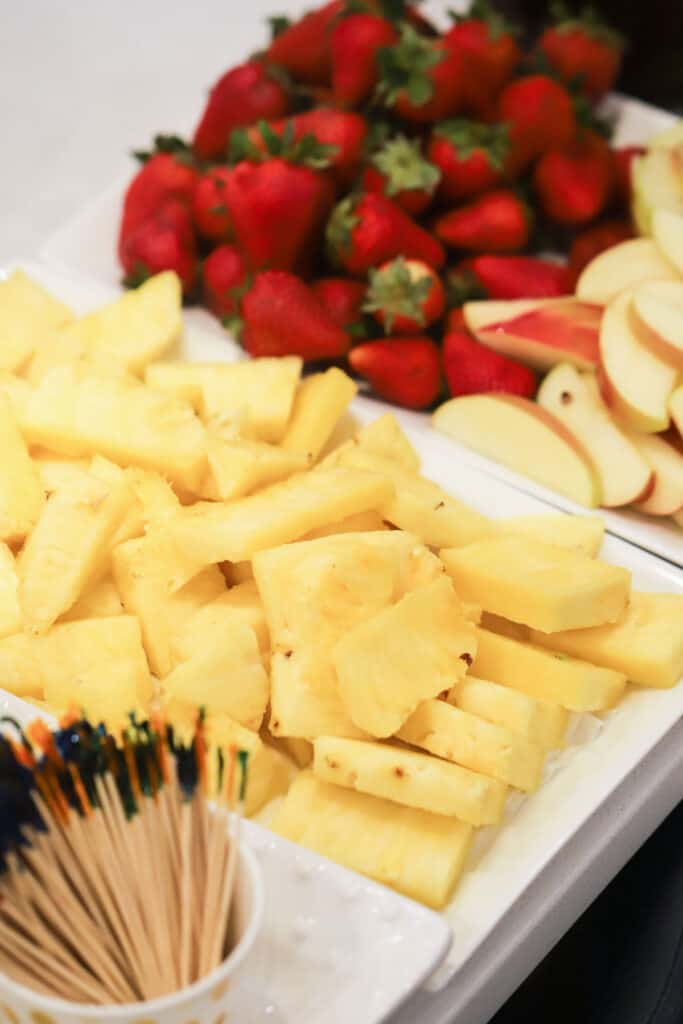 what to dip in Chocolate fountain, fresh pineapple wedges, whole strawberries, apples slices and a cup of toothpicks.