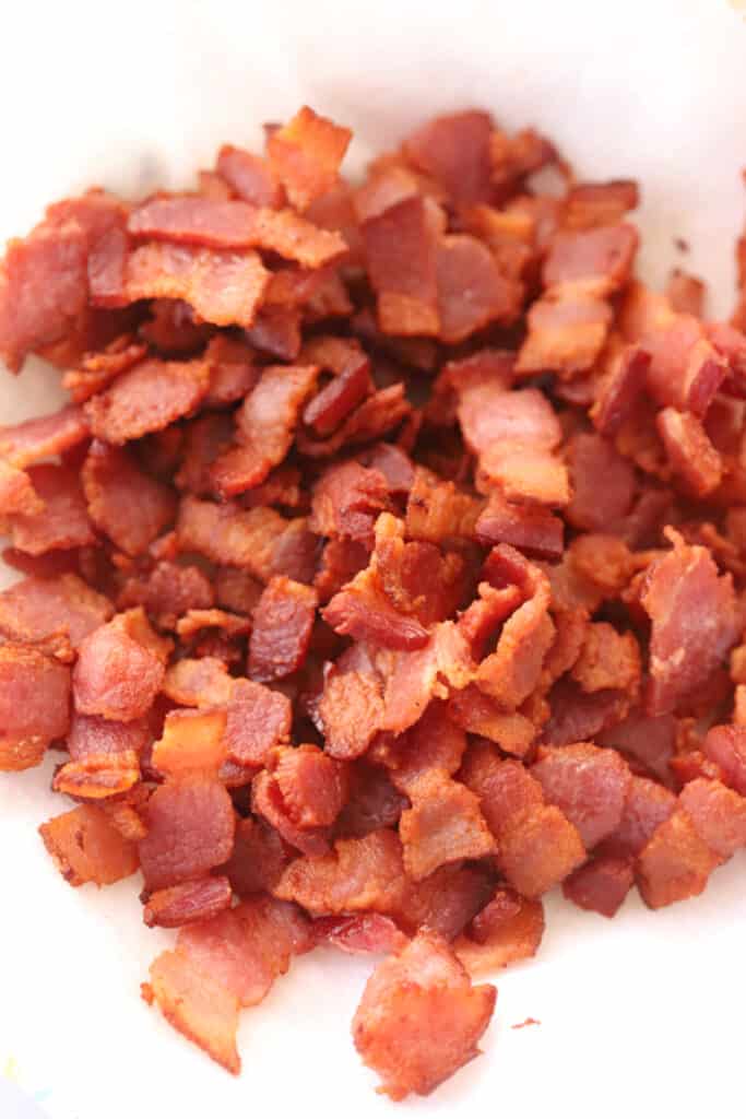 Homemade bacon bits on a paper plate, perfect for recipes with bacon and potatoes.