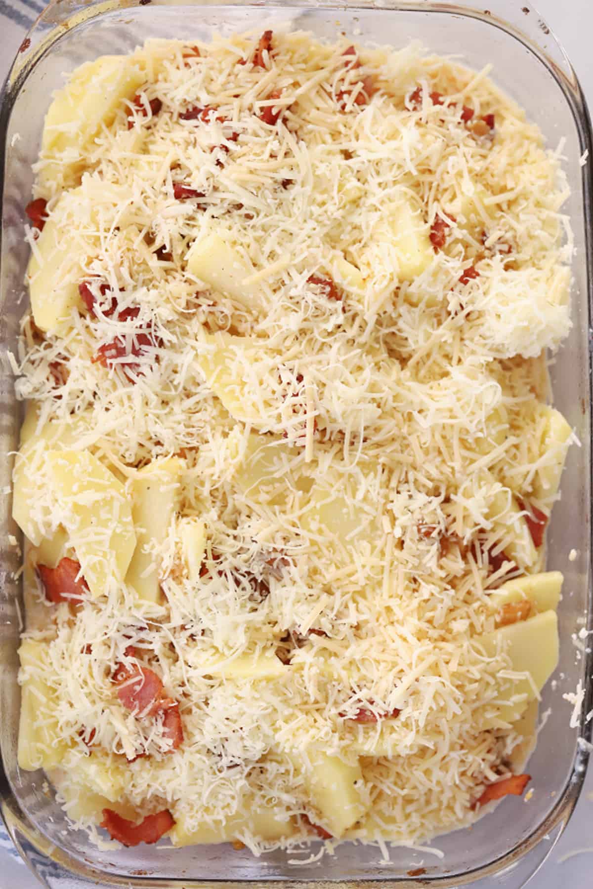 Smoky Bacon Potato Gratin 3 A baking dish full of scalloped potatoes topped with cheese and bacon.
