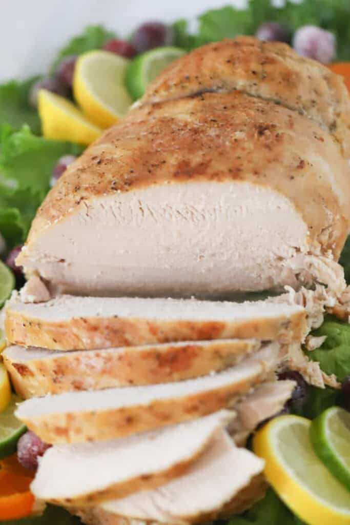 Sliced turkey breast on a serving platter surrounded by fresh lettuce garnish. Recipe for leftover turkey soup. 