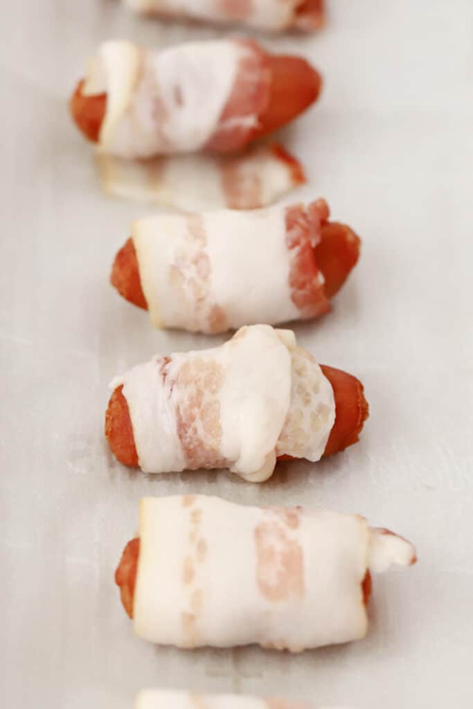 bacon wrapped smokies recipe, uncooked on a baking sheet.
