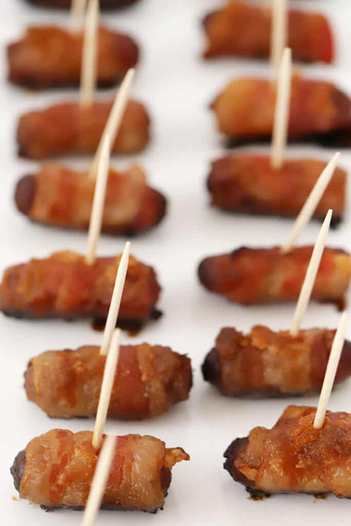 Bacon wrapped smokies with toothpicks on a baking sheet.
