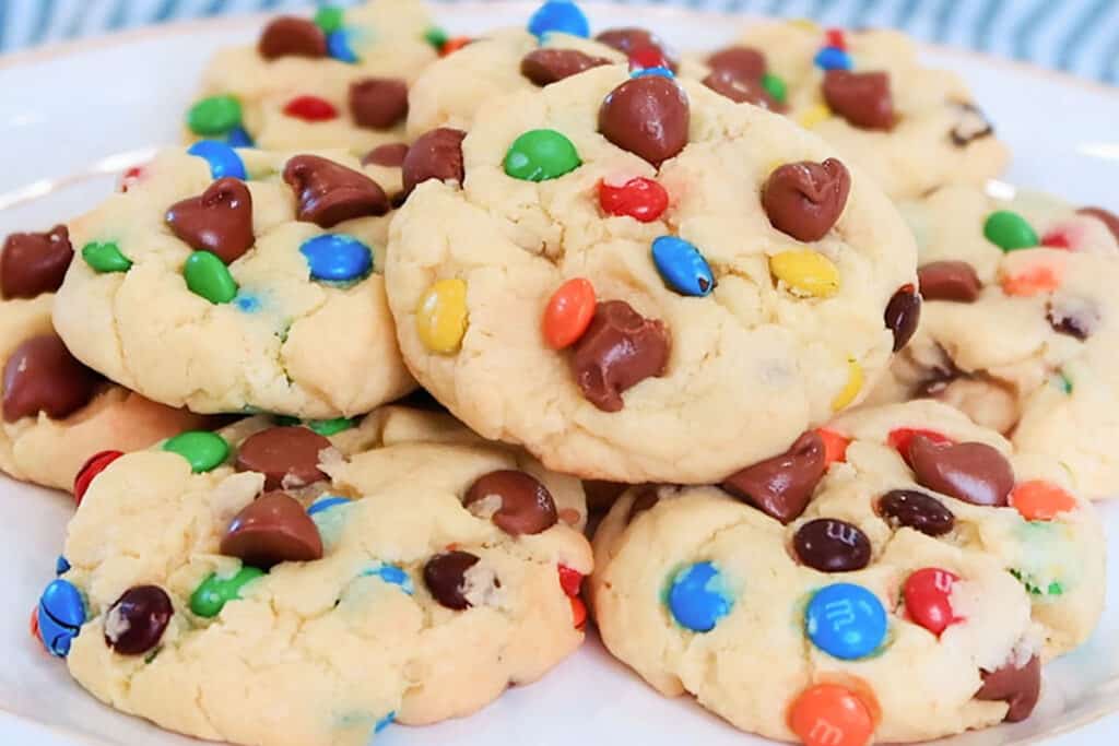 cake mix cookies with chocolate chips and m&Ms on a white plate.