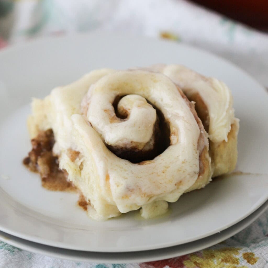 A cinnamon roll on a white plate, made using our recipe best cinnamon rolls.
