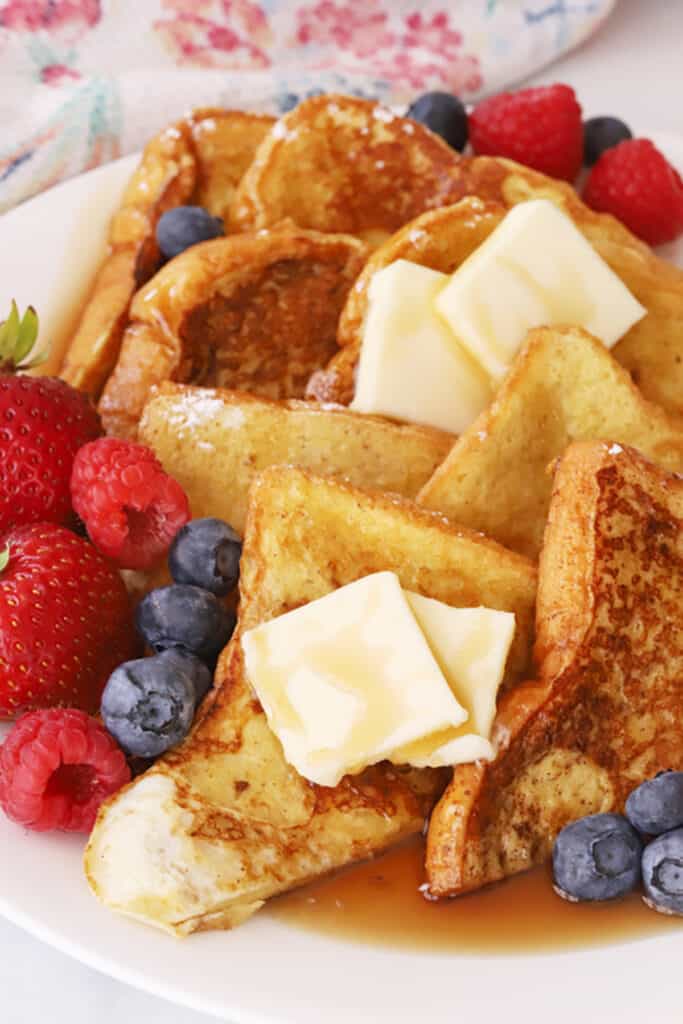 Classic french toast recipe, stacked on a plate with berries, butter and syrup, fancy french toast.
