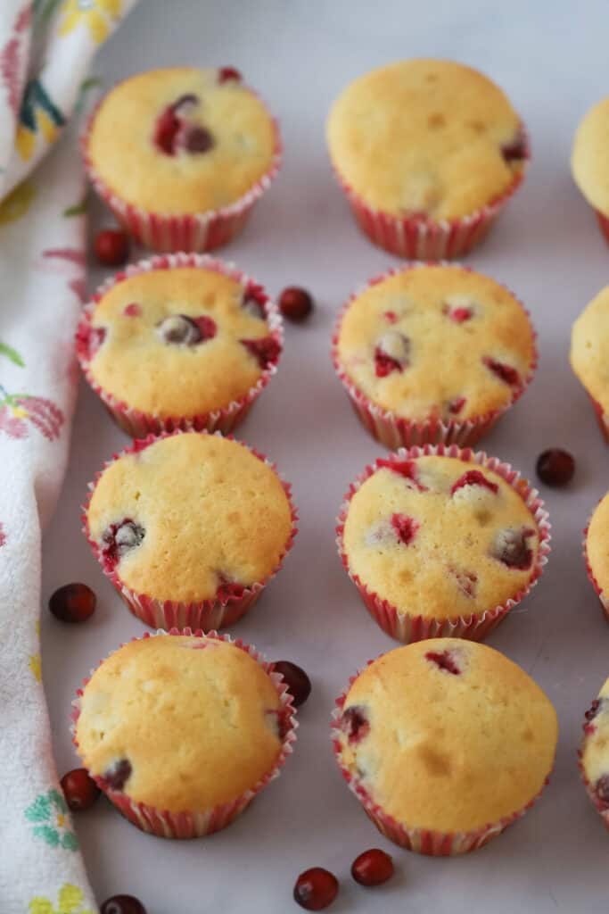 An easy orange cranberry muffin recipe, with cranberry muffins made with fresh cranberries in paper liners on a countertop.