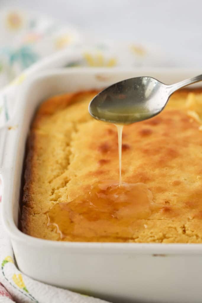 Creamed corn casserole in a baking dish with a drizzle of honey butter.